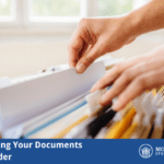 Person filing documents in file cabinet and folders